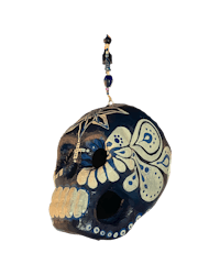 a blue and white sugar skull hanging on a black background