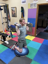 a man sitting on an exercise ball in a gym