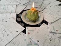 a candle sits on top of a pile of paper with writing on it