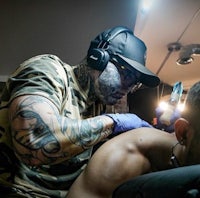 a tattoo artist is getting a tattoo on a man's back