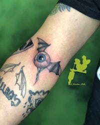 a tattoo on the arm with a bat and an eye