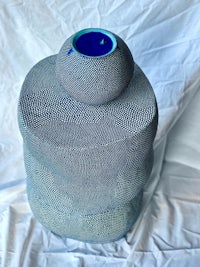a blue vase sitting on top of a white sheet