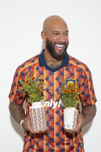 a man with a beard holding two pots of flowers
