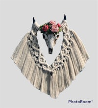 a cow skull with flowers and tassels on a white background