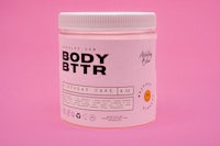 a jar of body bittr on a pink background