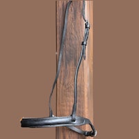 a black leather bridle hanging on a wooden pole