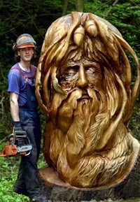 a man standing next to a wooden sculpture of a man with a beard