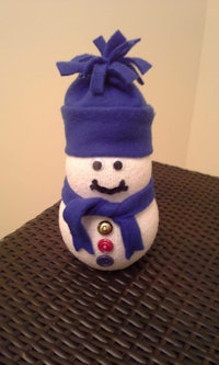 a snowman with a blue hat and scarf sitting on a table