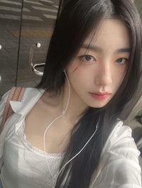 a girl with long black hair and earphones taking a selfie