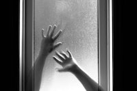 a black and white photo of two hands reaching out of a window