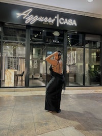 a woman in a black dress standing in front of a store