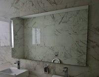 a marble bathroom with two sinks and a mirror