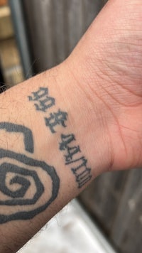 a man with a tattoo of a spiral on his wrist