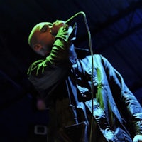 a man in a black jacket singing into a microphone