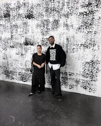two people standing in front of a large black and white painting