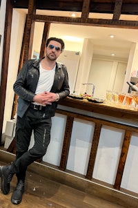 a man in a leather jacket standing in front of a bar