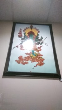a framed painting of a buddha on a wall