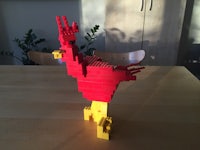 a red and yellow lego rooster on a table