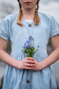a girl in a blue dress holding a bouquet of flowers