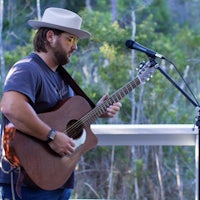 a man in a hat playing an acoustic guitar