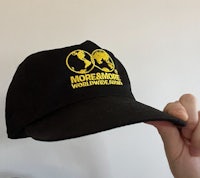 a person is holding up a hat with a yellow logo on it