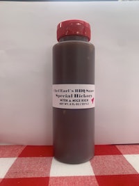 a bottle of bbq sauce on a red and white checkered tablecloth