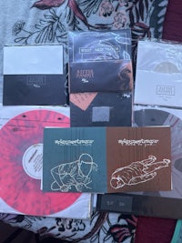 a collection of various cds and lps on a bed