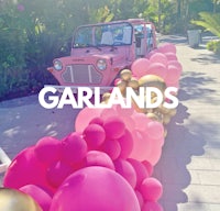 a pink jeep is parked next to pink balloons