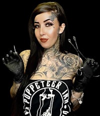 a woman with tattoos holding a pair of gloves