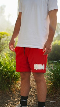 a man wearing red shorts and a white t - shirt