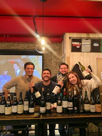a group of people posing with bottles of wine