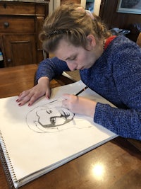 a girl drawing a face on a piece of paper