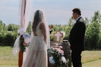 a bride and groom standing in front of a wine barrel