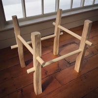 a wooden table with two legs in front of a window