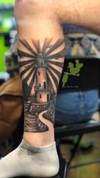 a tattoo of a lighthouse on a person's leg