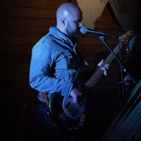 a bald man playing a bass in front of a microphone