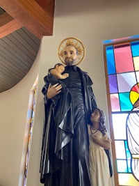 a statue of st joseph holding a child in front of stained glass windows