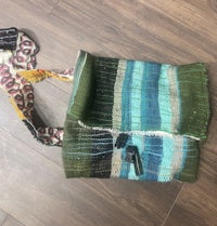 a green and blue striped bag on a wooden floor