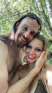 a man and woman hugging in the woods