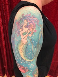 a woman with a mermaid tattoo on her arm