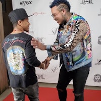 two men shaking hands on a red carpet