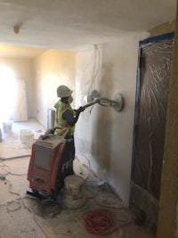 a man is painting a room with a paint sprayer