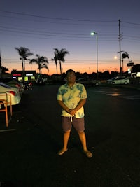a man standing in a parking lot at sunset