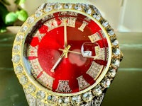 a red watch with diamonds and roman numerals