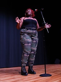 a woman in camouflage pants standing on stage