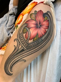 a woman's thigh tattooed with a hibiscus flower