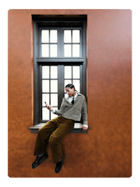 a man sitting on a window sill with a cell phone