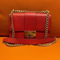 a red leather bag with a gold chain on it