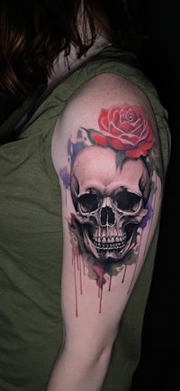 a woman with a skull and rose tattoo on her arm