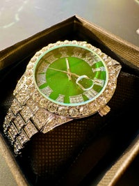 a green and silver watch in a box